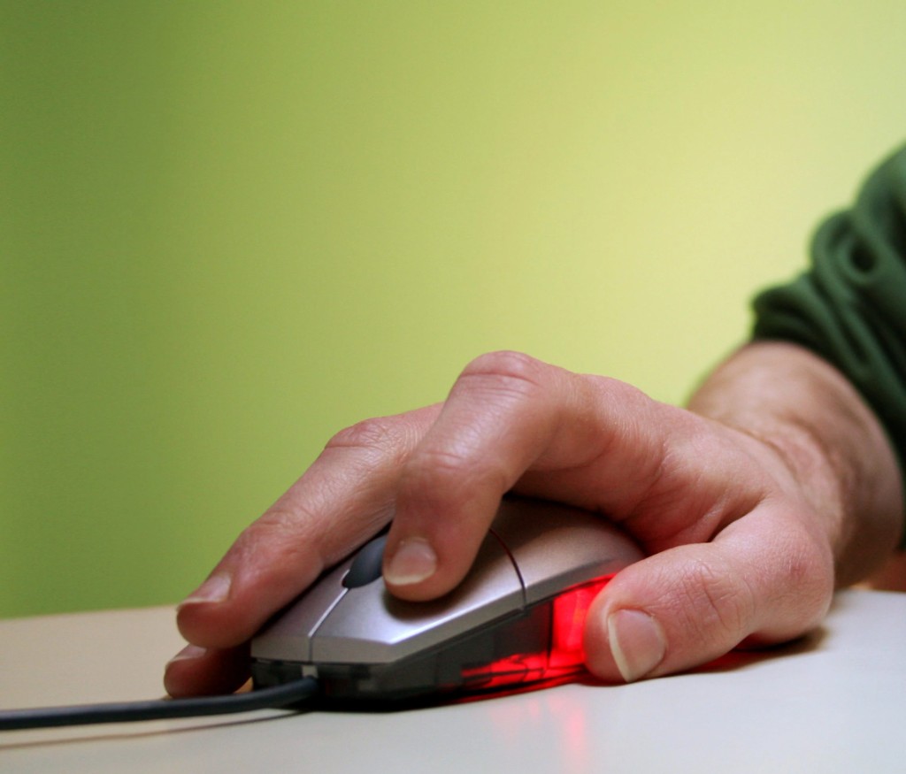 A hand rests on a computer mouse against a green background